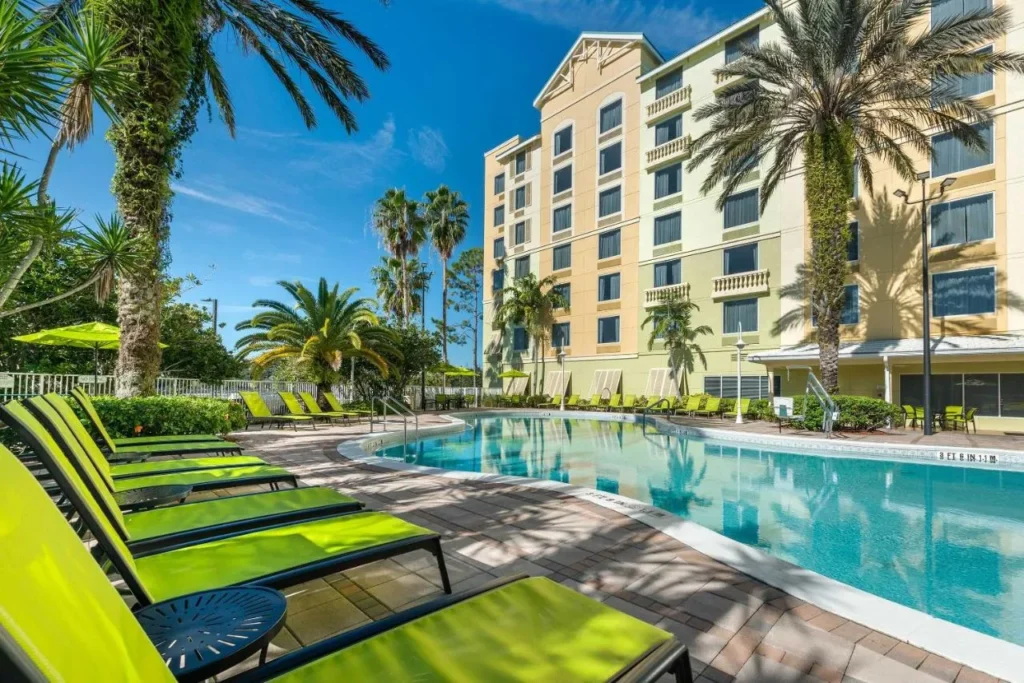 Piscina climatizada al aire libre con tumbonas verdes debajo de la torre de Comfort Suites Maingate East