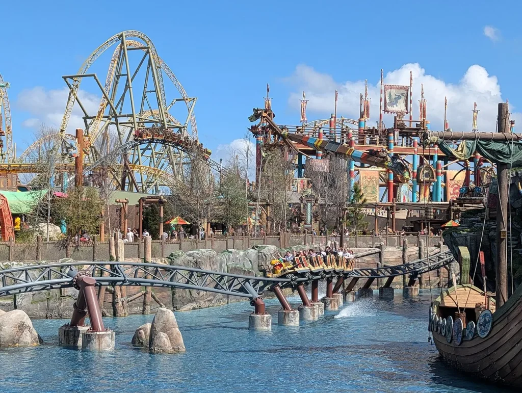 Hiccup's Wing Gliders coaster train crossing the lagoon beside a Viking ship, Isle of Berk