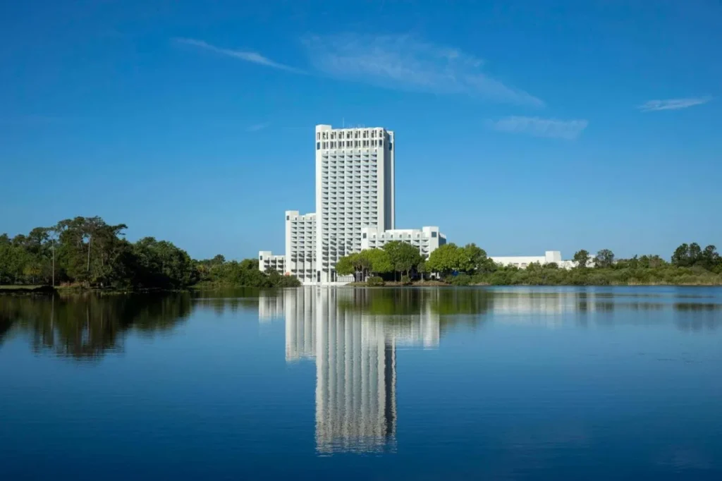 Hilton Orlando Buena Vista Palace torre reflejada en un lago tranquilo bajo un cielo azul claro