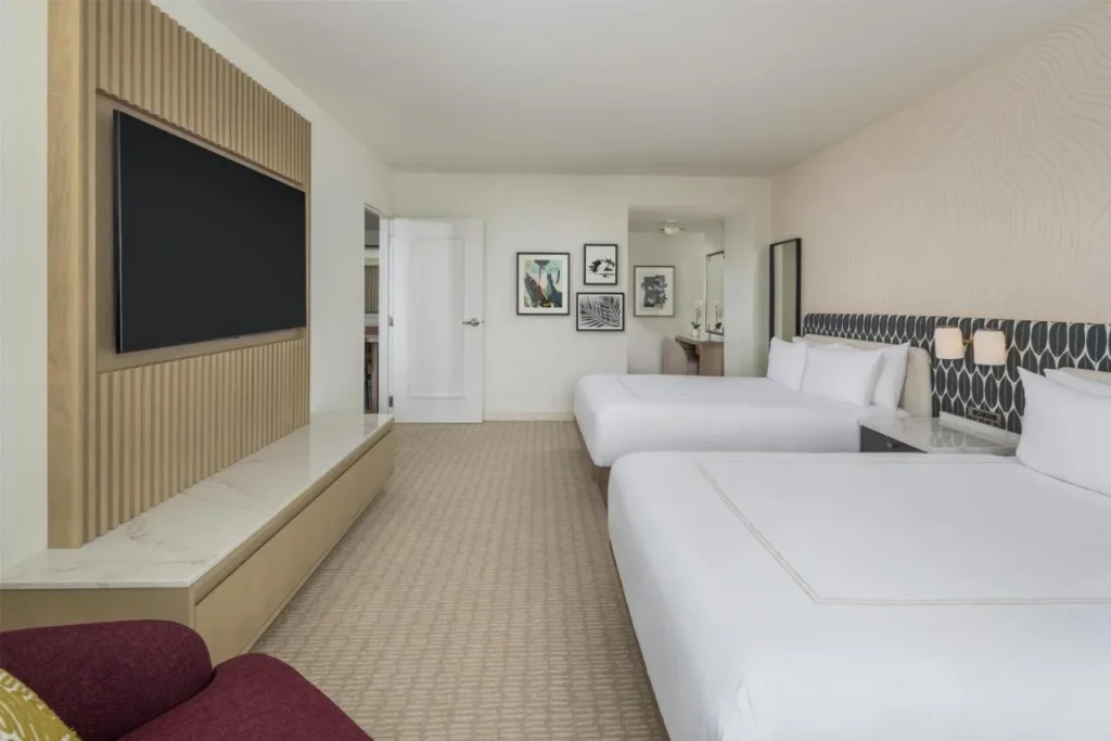 Habitaci&oacute;n Hilton Orlando con dos camas queen, TV de pared grande y sof&aacute; rojo