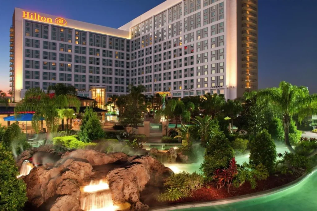 Hilton Orlando torre iluminada al atardecer sobre cascadas de roca y el r&iacute;o lento