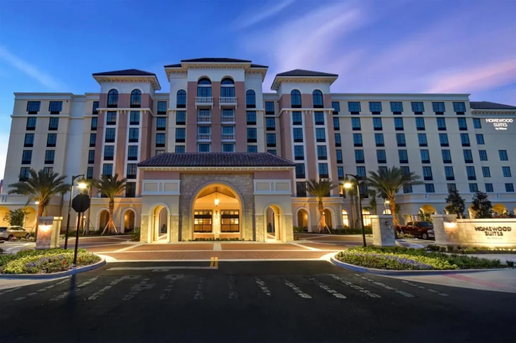 Homewood Suites Flamingo Crossings arched entrance, porte-cochere and lit sign at dusk