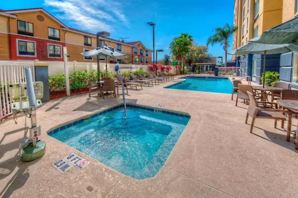 Hot tub and outdoor pool with loungers and umbrellas at Fairfield Inn & Suites Near Universal