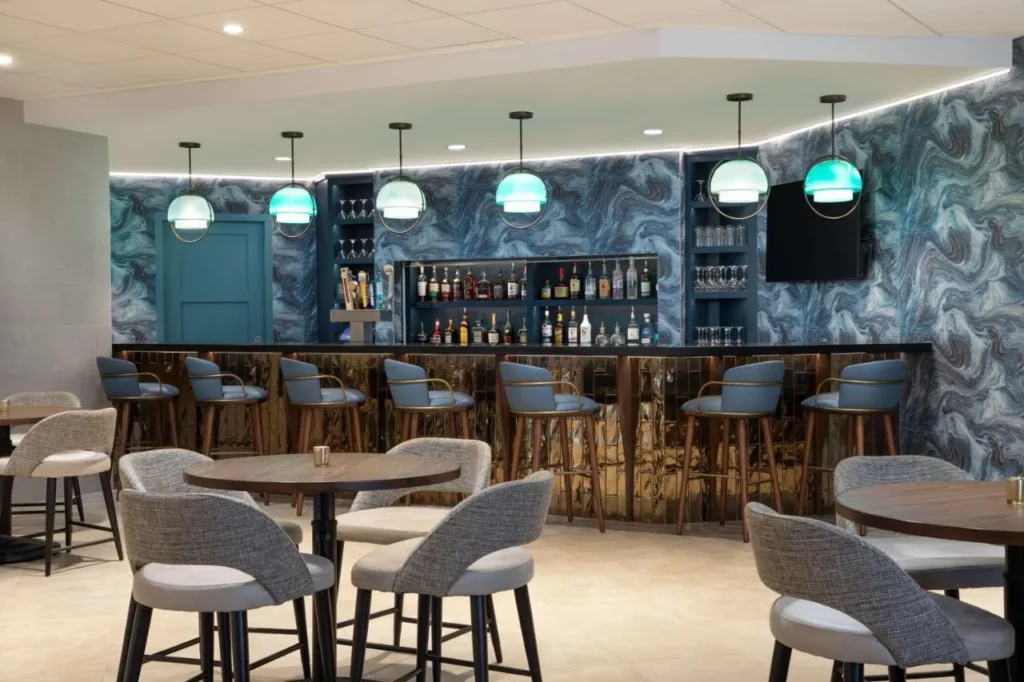 Bar del hotel con paredes de m&aacute;rmol azul y mesas altas en DoubleTree Suites Disney Springs