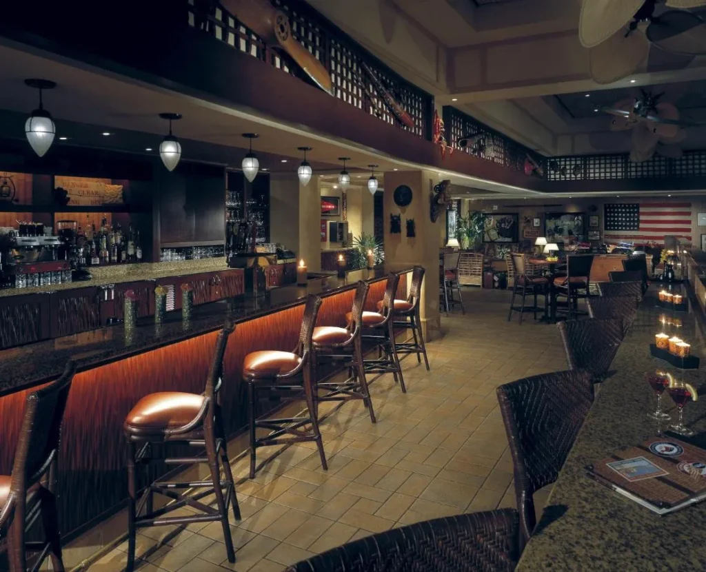 Hotel bar with leather stools, pendant lamps and an American flag at Loews Royal Pacific Resort