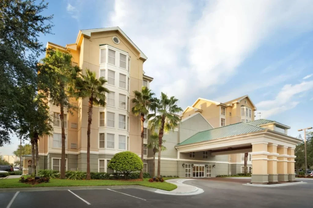 Edificio hotelero con palmeras y techos verdes en Homewood Suites by Hilton Orlando-International Drive