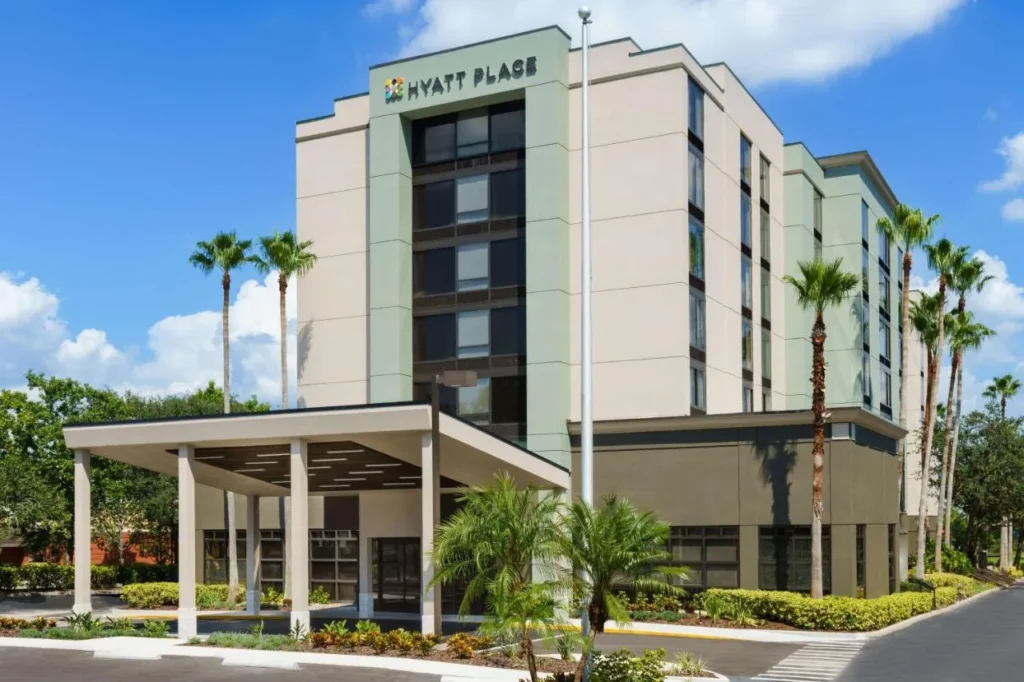 Exterior del hotel con entrada cubierta y palmeras en el Hyatt Place Orlando I-Drive Convention Center