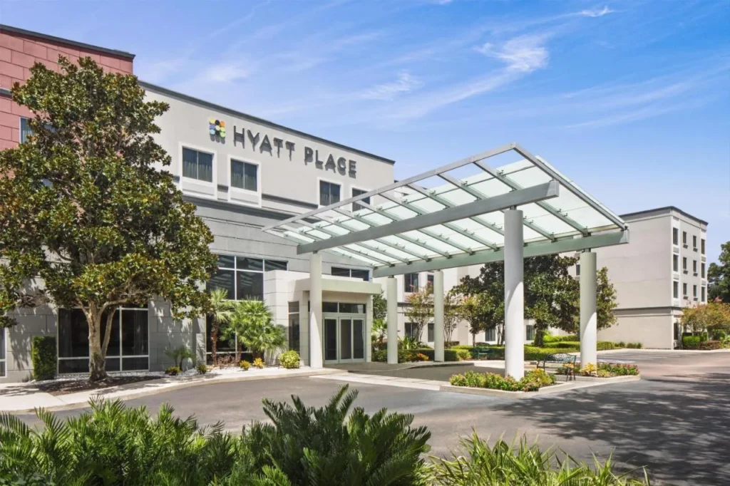 Hyatt Place Lake Mary/Orlando-North entrada con dosel de cristal, magnolia árbol y unidad ajardinada