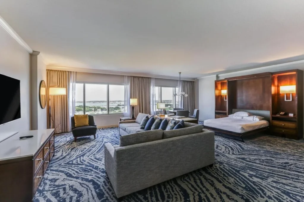 Suite Hyatt Regency Orlando con cama plegable en la pared, dos sof&aacute;s y amplias ventanas con vistas al lago