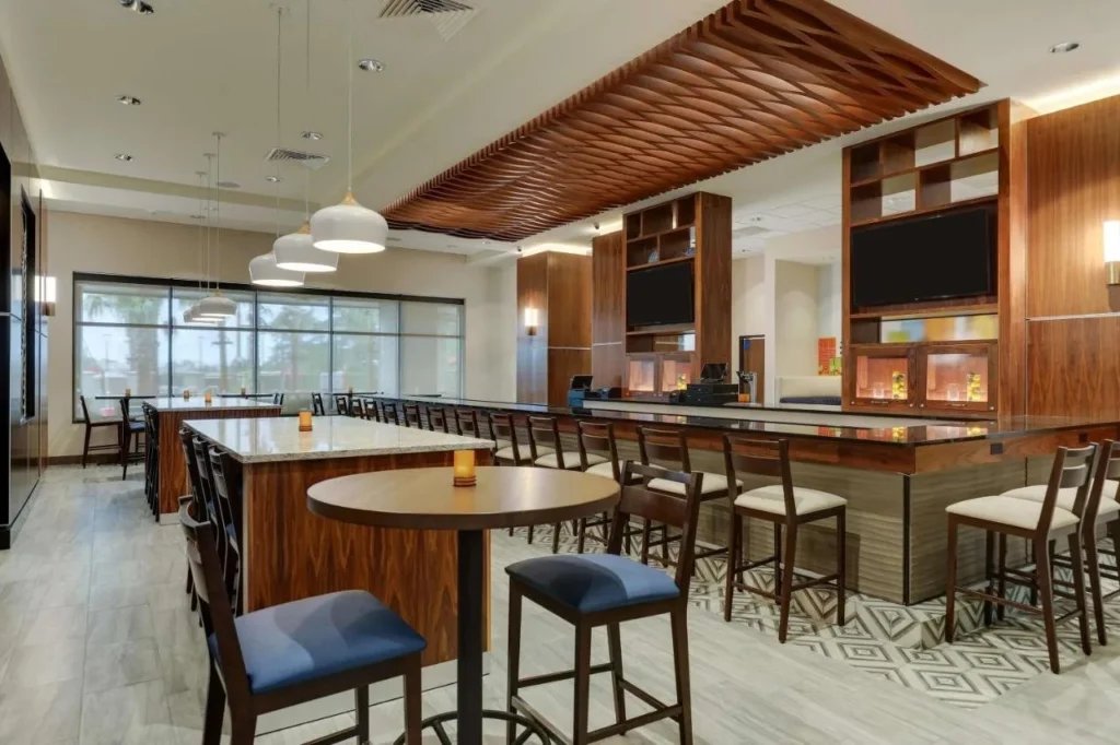 Bar y comedor interior en Drury Plaza Hotel Orlando con mesas y taburetes de alta gama