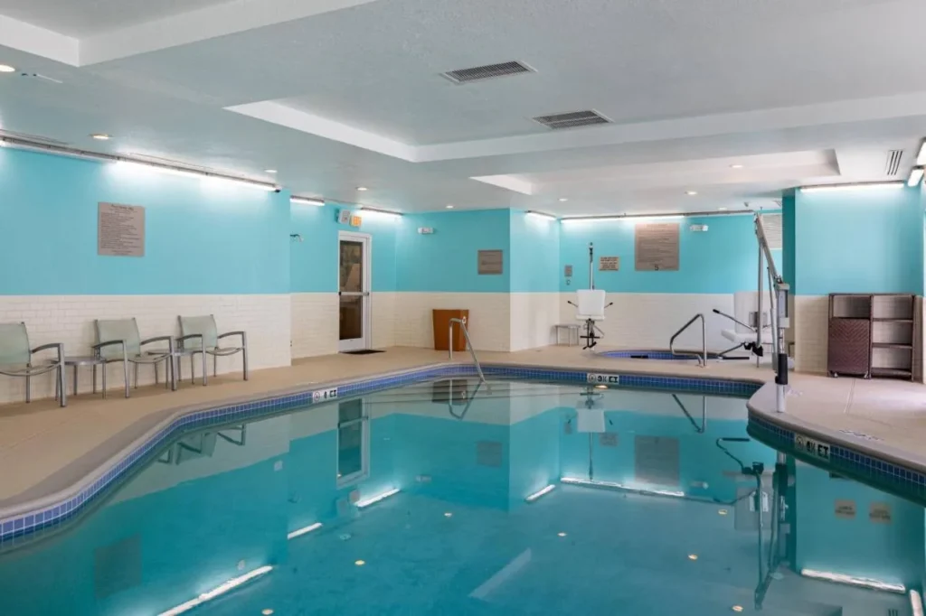 Indoor pool with aqua walls, poolside chairs and a pool lift at SpringHill Suites Orlando Altamonte Springs