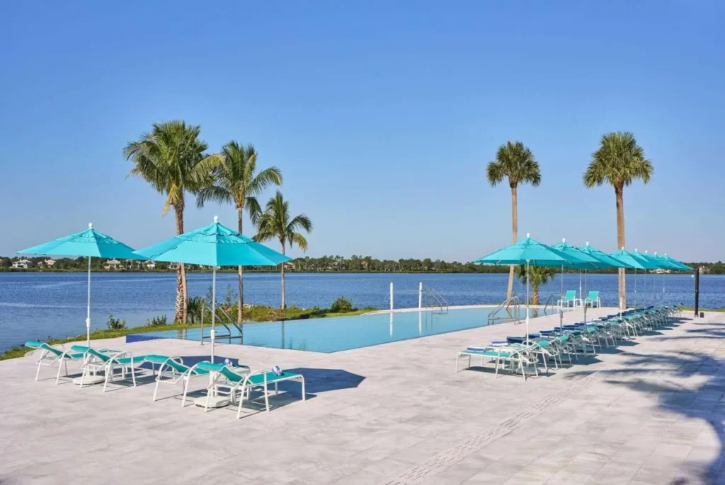 Piscina infinita con sombrillas de verde azulado junto a la calle. Lucie River at voco Sandpiper Complejo turístico con todo incluido