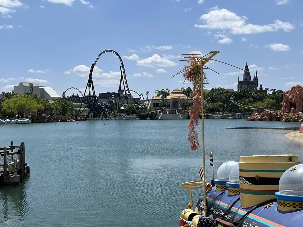 Islands of Adventure lagoon with the VelociCoaster loop and Hogwarts castle on the skyline