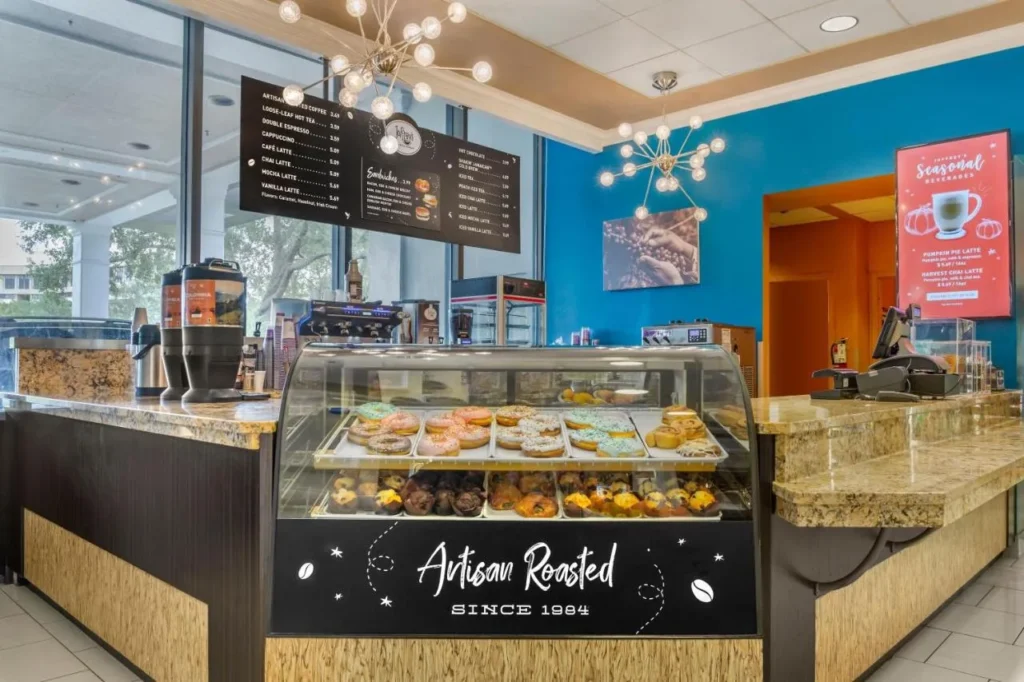 El mostrador de caf&eacute; de Joffrey con una caja de pasteler&iacute;a y tableros de men&uacute; en Wyndham Lake Buena Vista