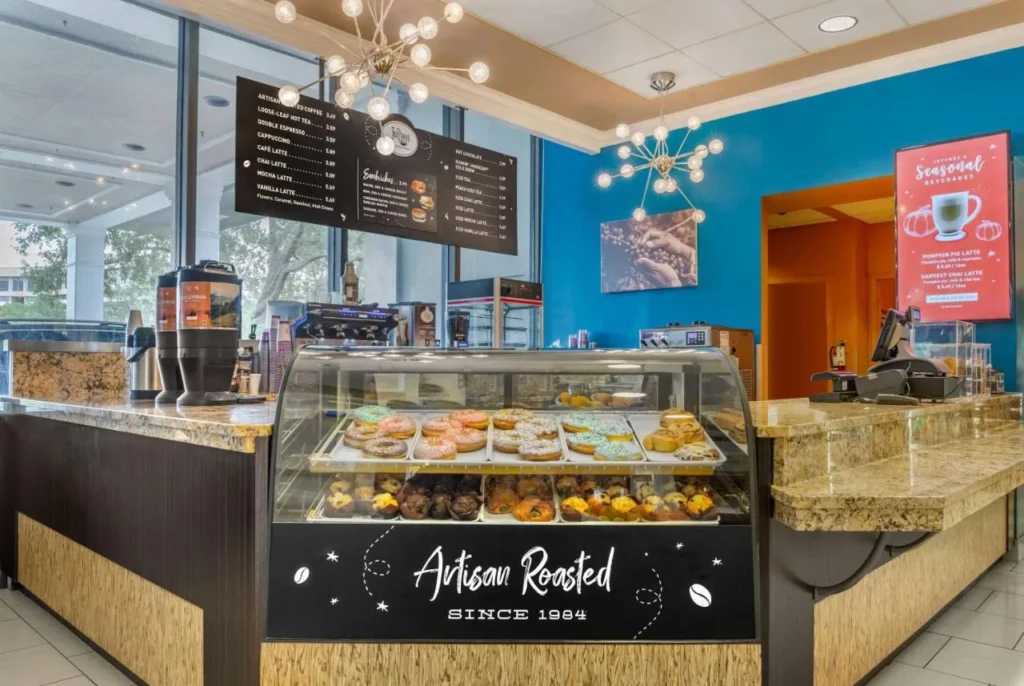 El mostrador de caf&eacute; de Joffrey con una caja de pasteler&iacute;a y tableros de men&uacute; en Wyndham Garden Lake Buena Vista