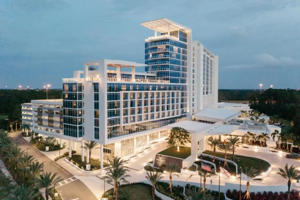 JW Marriott Orlando Bonnet Creek Resort torre y unidad de entrada bordeada de palmeras iluminada al atardecer