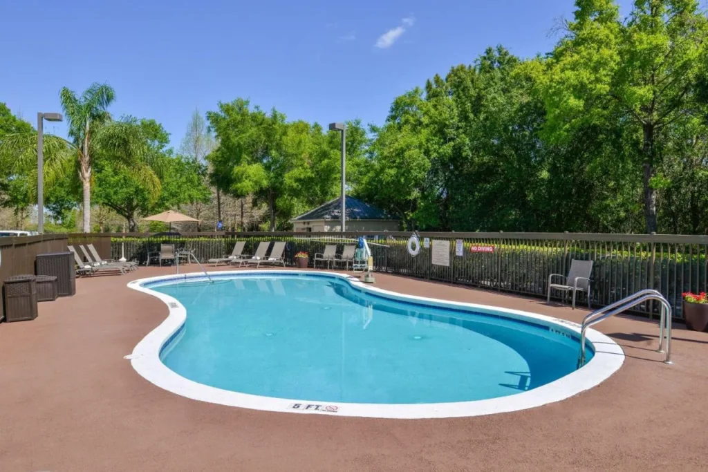 Kidney-shaped outdoor pool with loungers and a fenced deck at Hampton Inn Closest to Universal Orlando