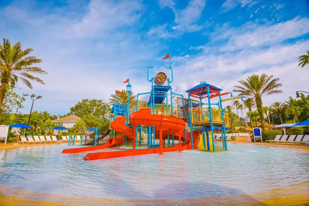 Kids' splash zone with red slides and a play tower at the Reunion Resort water park