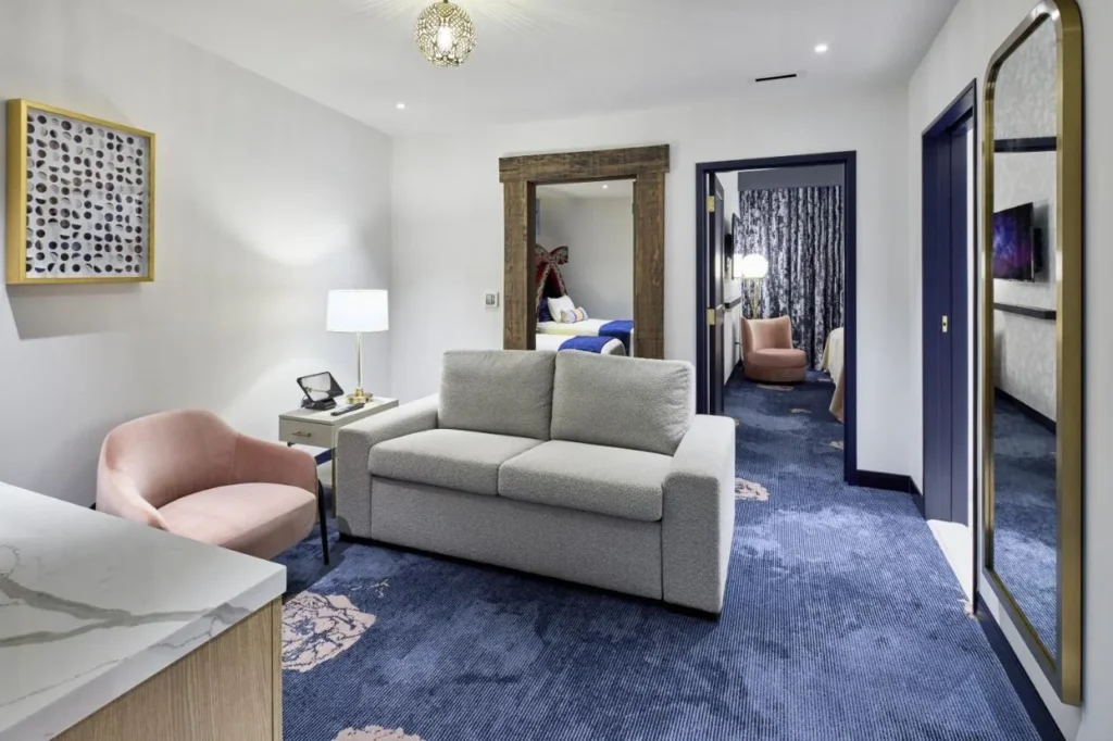 Kids' suite living area with a sofa and dragon-themed bedroom beyond, Universal Helios Grand Hotel