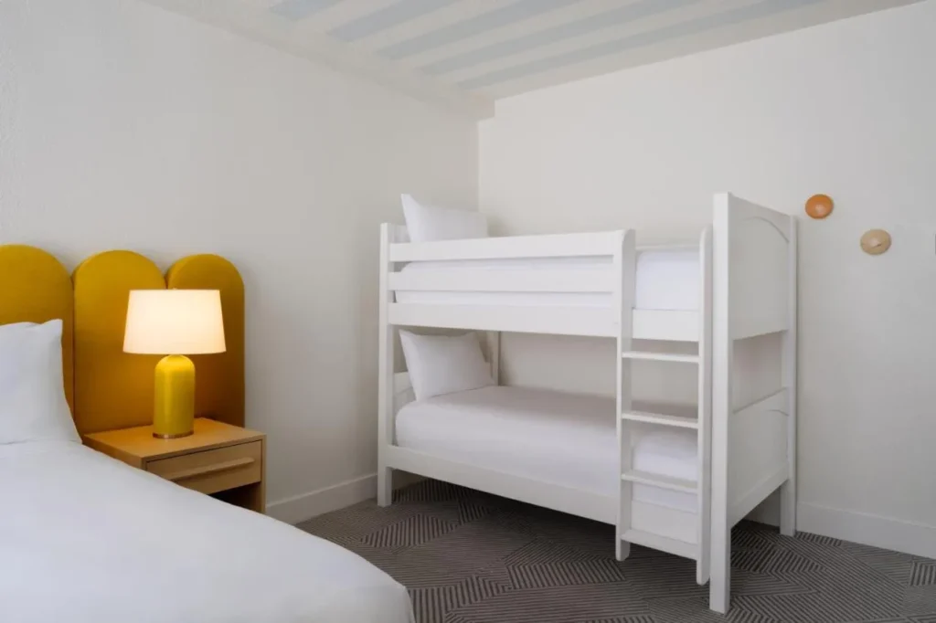 Literas blancas para niños junto a una cama con cabecero amarillo en Renaissance Orlando Resort
