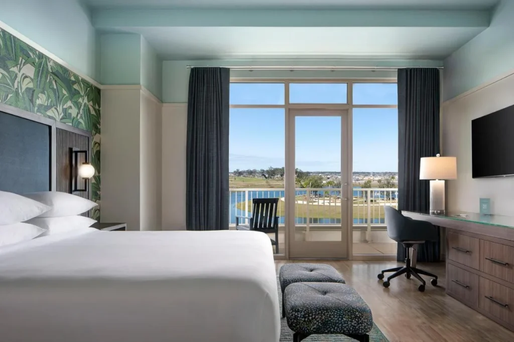 Habitaci&oacute;n con balc&oacute;n king con escritorio y puerta de cristal a un balc&oacute;n con vistas al lago en el Hotel Eastport