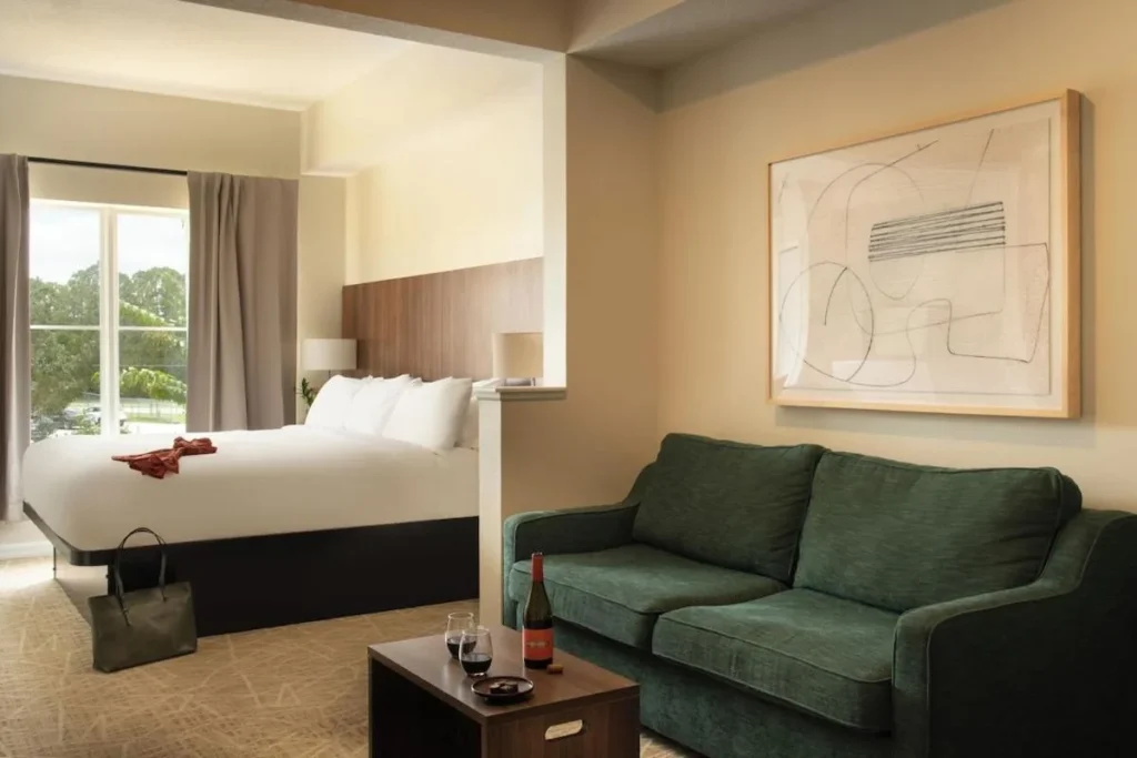Cama King y sof&aacute; verde en una suite de estilo estudio en The Point Hotel & Suites