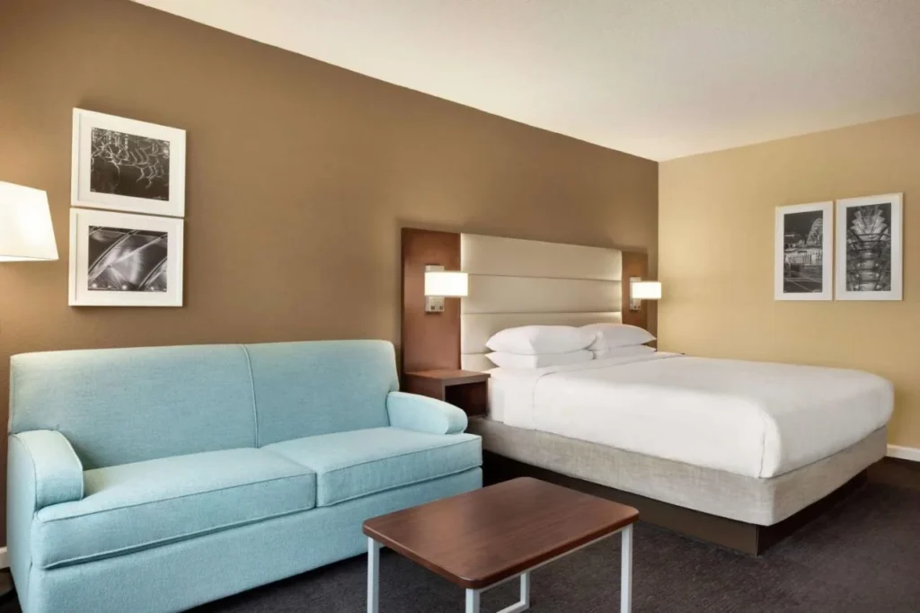 Cama King junto a un sof&aacute; azul claro y una mesa de centro en DoubleTree by Hilton Orlando Downtown