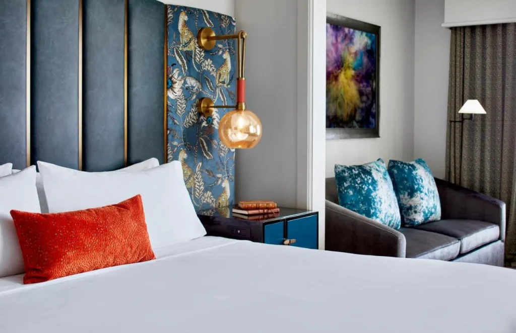 King bed beside a small sofa and colorful abstract artwork in a Hotel Beauden room