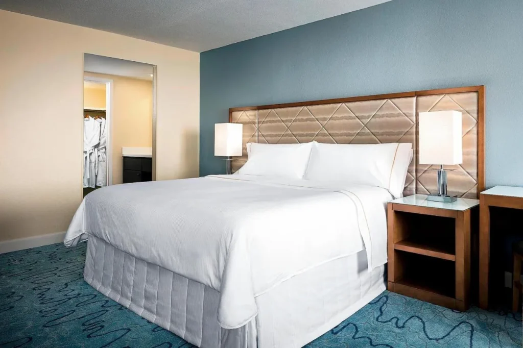 King bed with a padded headboard and a closet with robes at Walt Disney World Dolphin