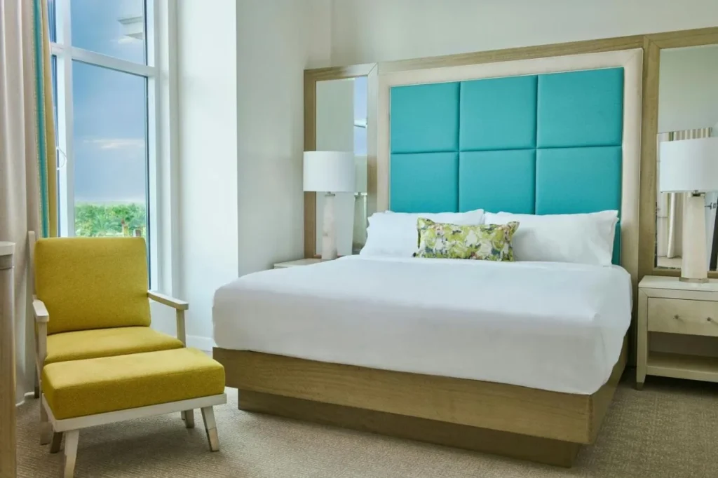 Cama king con cabecero acolchado turquesa y sillón amarillo en Gaylord Palms Resort