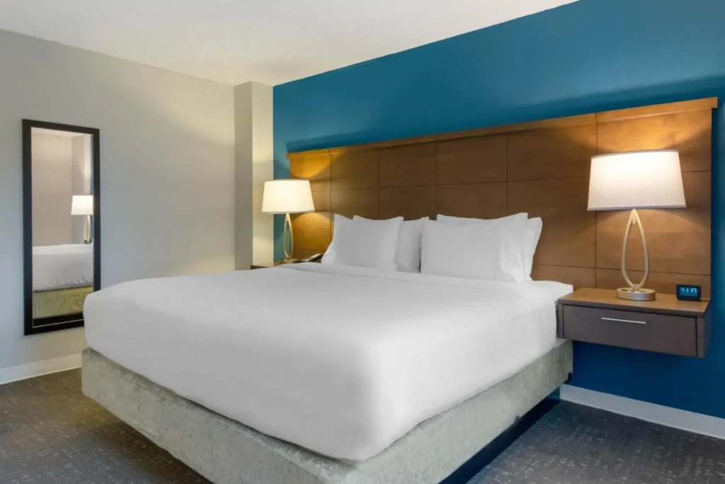 King bed with a wood headboard and blue accent wall at Staybridge Suites Royale Parc