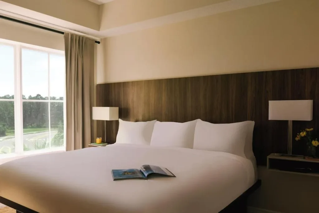 Cama king con cabecera de madera junto a una gran ventana en The Point Hotel & Suites
