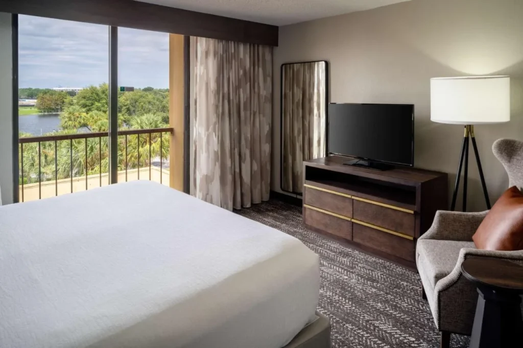 Habitaci&oacute;n con cama king en el Embassy Suites Orlando North con balc&oacute;n y vistas al lago