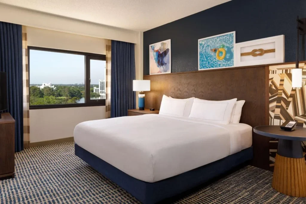 Habitaci&oacute;n King con una pared de acento azul marino y una vista de la ventana en DoubleTree Suites Disney Springs