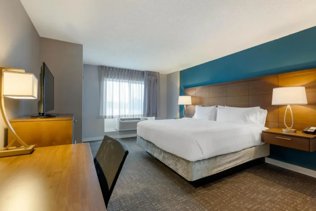 King bedroom with a teal accent wall, desk and TV at Staybridge Suites Royale Parc