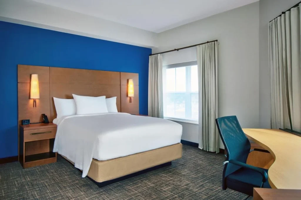 Habitaci&oacute;n con cama king y pared con acento azul, escritorio y silla en el Residence Inn Flamingo Crossings