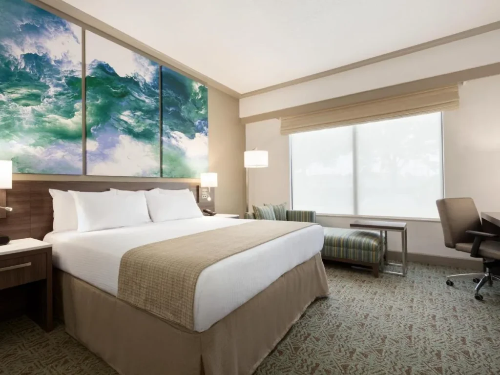 Dormitorio king con arte de la pared océano-ola, tumbona y silla de escritorio en Buena Vista Suites