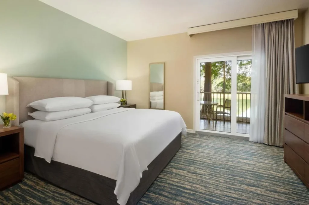 Dormitorio King con puerta corredera a un balcón amueblado con vistas a los árboles en Sheraton Vistana Resort