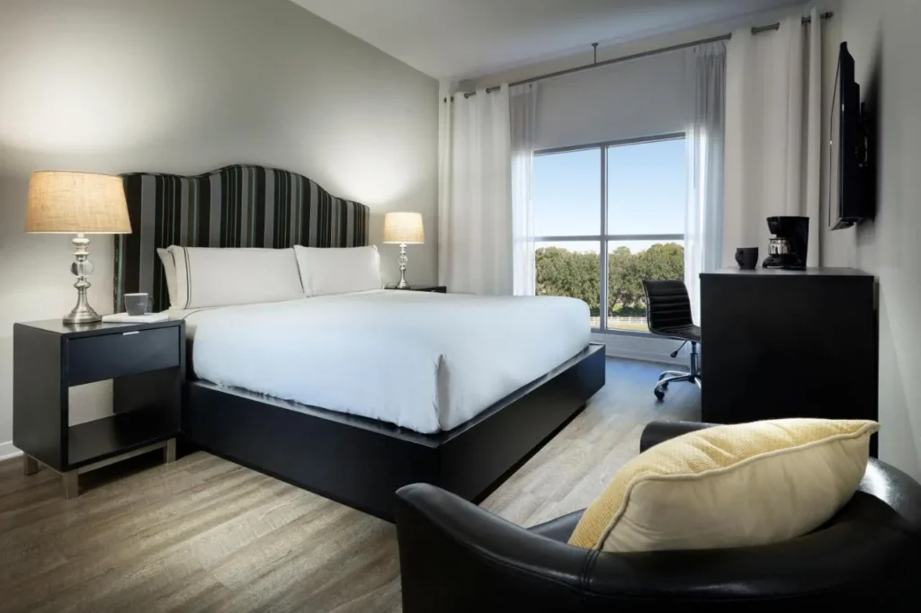 Dormitorio King con cabecera a rayas, silla de escritorio y ventana con vista al árbol en Meliá Orlando Celebration