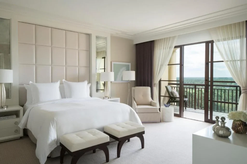 King bedroom with tufted headboard and open balcony doors at Four Seasons Resort Orlando
