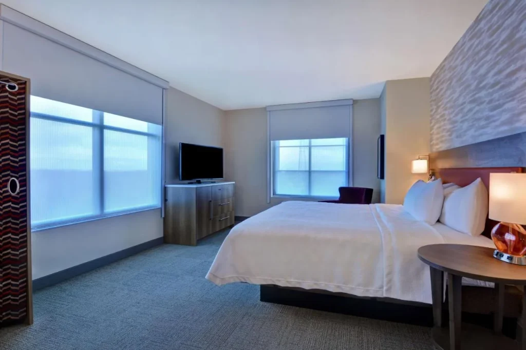Habitación King con dos ventanas y una cómoda con TV en el Home2 Suites Flamingo Crossings