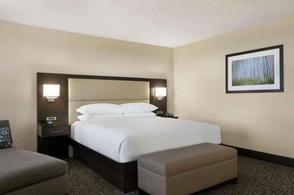 Habitaci&oacute;n con cama king en Hilton Orlando/Altamonte Springs con cabecera acolchada, banco y sill&oacute;n