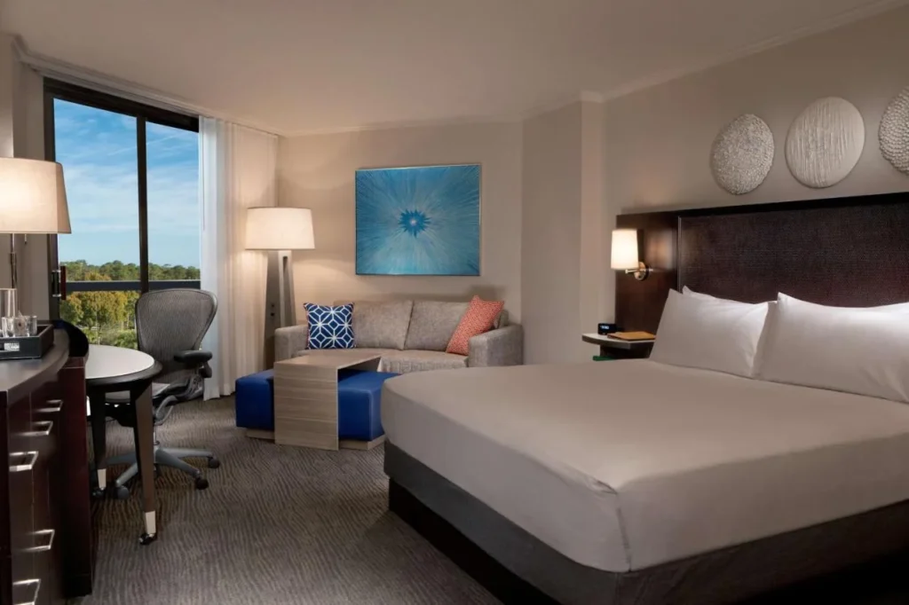 Habitaci&oacute;n con cama king en el Hilton Orlando Buena Vista Palace con sof&aacute;, escritorio y ventana grande