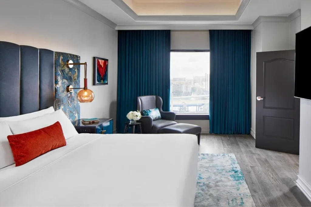King guest room with blue velvet headboard, armchair and a downtown window view at Hotel Beauden