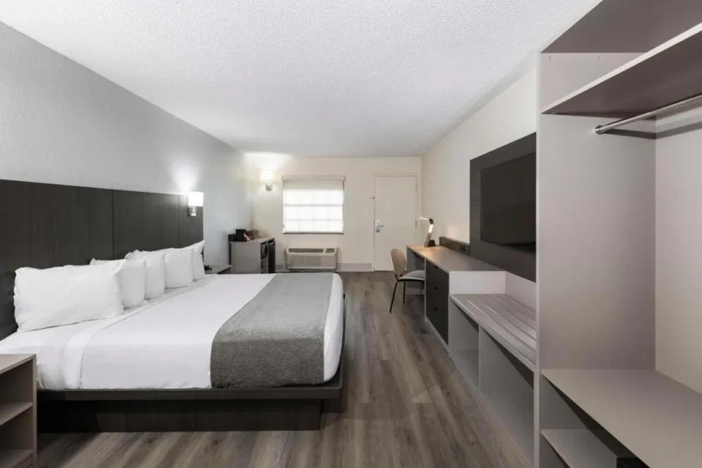 Habitaci&oacute;n con cama king con cabecera oscura, TV de pared y escritorio de trabajo en Avanti International Resort