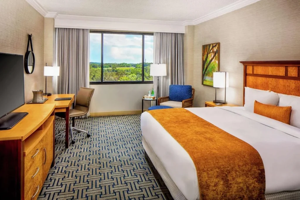 Habitaci&oacute;n King con escritorio, sill&oacute;n y ventana sobre las copas de los &aacute;rboles verdes en Hilton Ocala