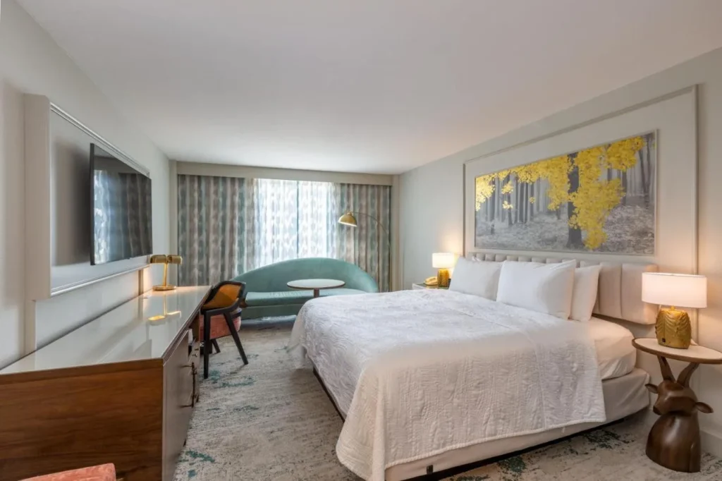 King room at Castle Hotel Orlando with gold forest artwork, a teal sofa and long desk