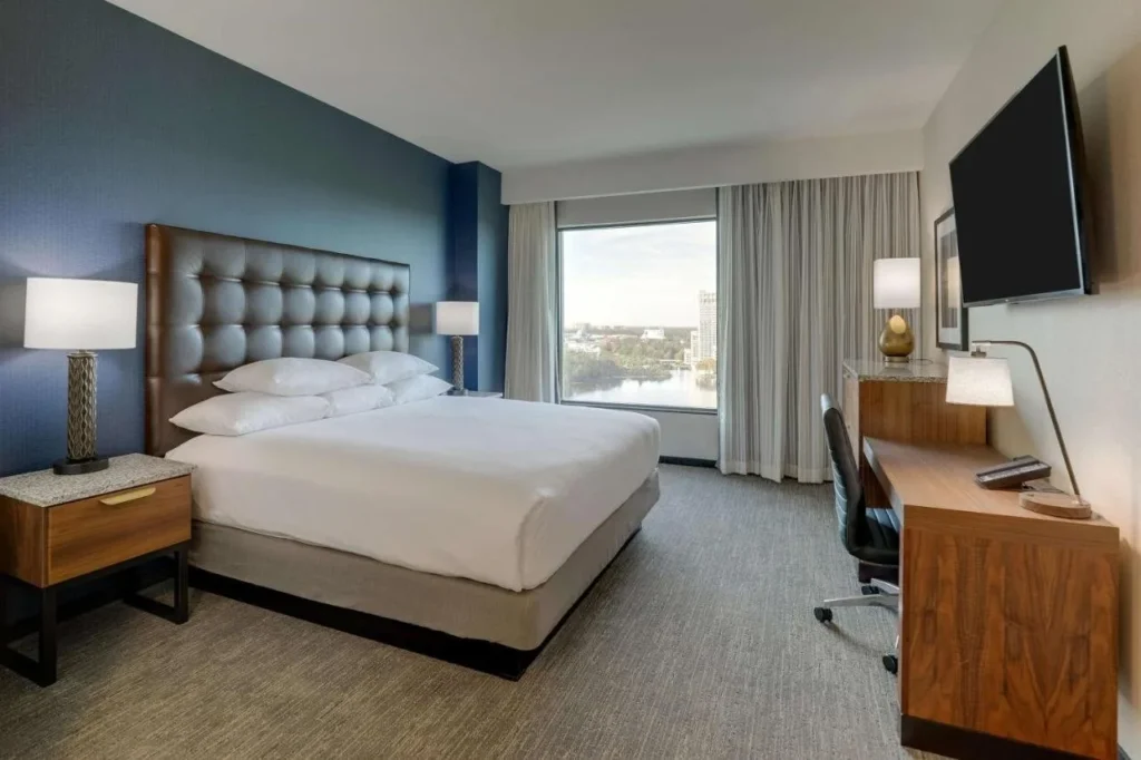Habitación con cama king en el Drury Plaza Hotel Orlando con escritorio, TV y ventana con vistas al lago