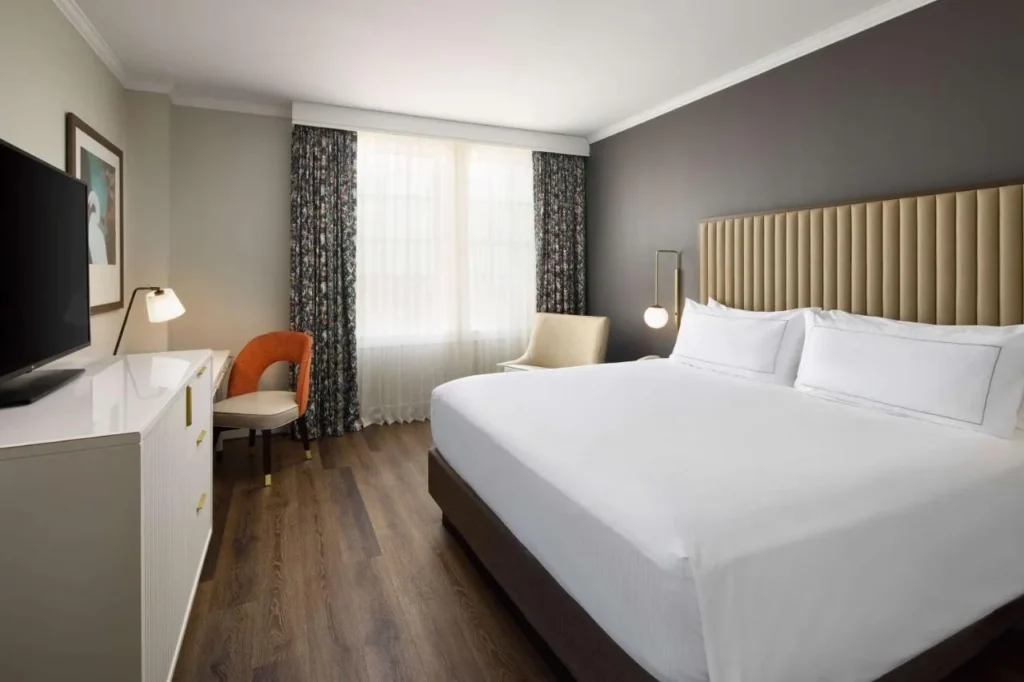 Habitación con cama king en The Terrace Hotel Lakeland con cabecera acolchada, suelo de madera y escritorio