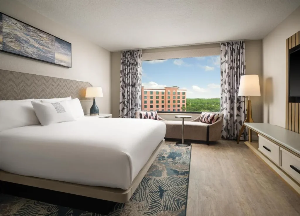 King room with a chaise by a window facing a resort tower at Caribe Royale Orlando